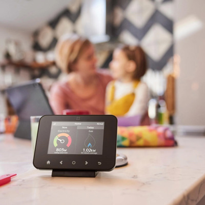 Image Of A Smart Meter In The Foreground With A Mother And Child Sitting In The Background