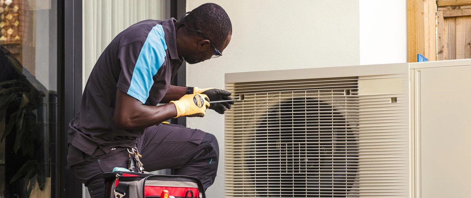 British gas engineer kneeling down fixing a unit outside