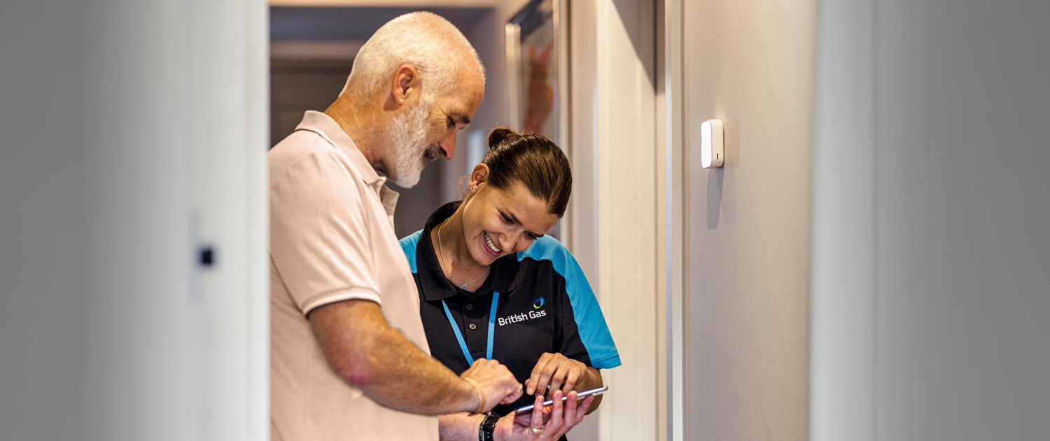 British Gas Engineer Looking At A Phone With A Customer